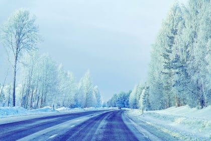 Une femme porte une veste d'hiver et une écharpe alors qu'elle se prépare à voyager dans des conditions hivernales. Elle est entourée de bagages et vérifie attentivement ses précautions pour s'assurer d'un voyage en toute sécurité.