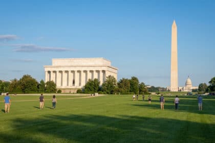 Vue panoramique du National Mall avec le Mémorial de Lincoln, le Washington Monument et le Capitole. Des visiteurs se promènent sur la pelouse.