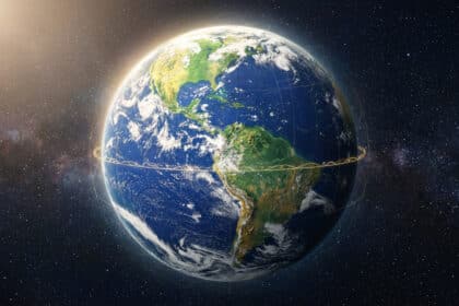 Vue de la Terre depuis l'espace, montrant les Amériques illuminées par le soleil. Des lignes dorées lumineuses entourent la planète sur fond étoilé.
