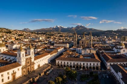Vue aérienne de Quito avec la Basilique du Voto Nacional et l'église San Francisco, montagnes enneigées en arrière-plan.