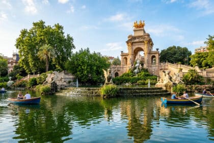 Barques sur le lac du parc de la Ciutadella devant la fontaine monumentale à Barcelone sous un ciel bleu.