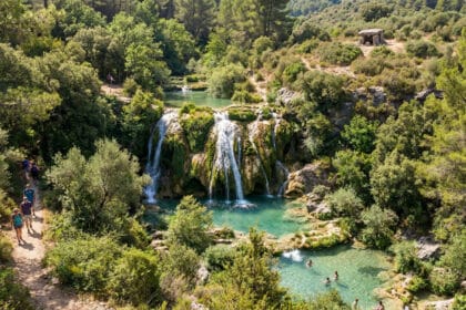 Randonneurs près d'une cascade entourée de forêts avec des baigneurs dans un bassin turquoise à Escragnolles.