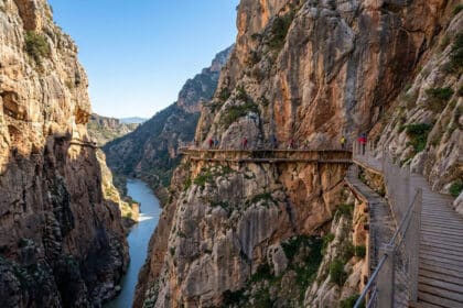 Randonneurs marchant sur une passerelle en bois suspendue à flanc de falaise au Caminito del Rey en Espagne.