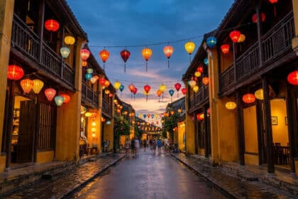 Rue historique de Hoi An avec des lanternes colorées suspendues au-dessus des maisons jaunes traditionnelles au crépuscule.