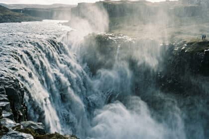 Vue panoramique de la puissante cascade de Dettifoss en Islande avec des touristes observant depuis le bord de la falaise.