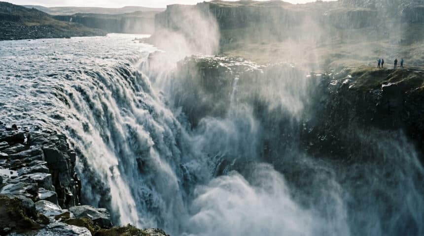 Vue panoramique de la puissante cascade de Dettifoss en Islande avec des touristes observant depuis le bord de la falaise.