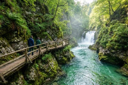 Deux personnes marchent sur une passerelle en bois longeant une rivière turquoise dans la gorge de Vintgar.