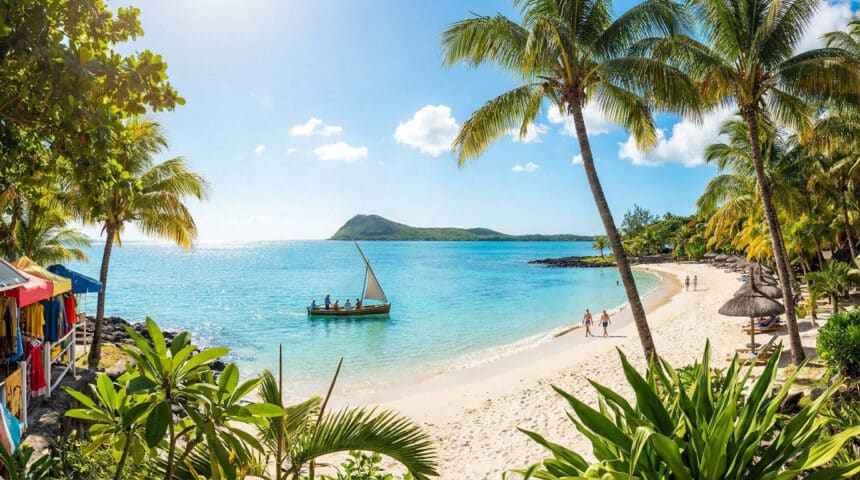Vue panoramique d'une plage tropicale à Grand Baie avec un voilier traditionnel, des cocotiers et une eau turquoise.