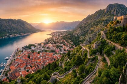 Vue panoramique de la baie de Kotor avec ses toits rouges, ses remparts et les montagnes au coucher du soleil.