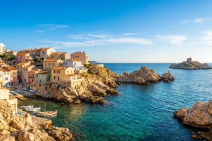Maisons colorées surplombant le petit port et les eaux turquoise de Malmousque à Marseille sous un ciel bleu.