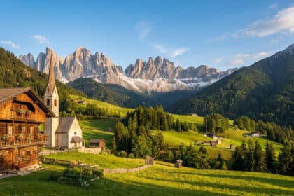 Vue panoramique d'un village alpin traditionnel avec église au pied des sommets enneigés des Dolomites.
