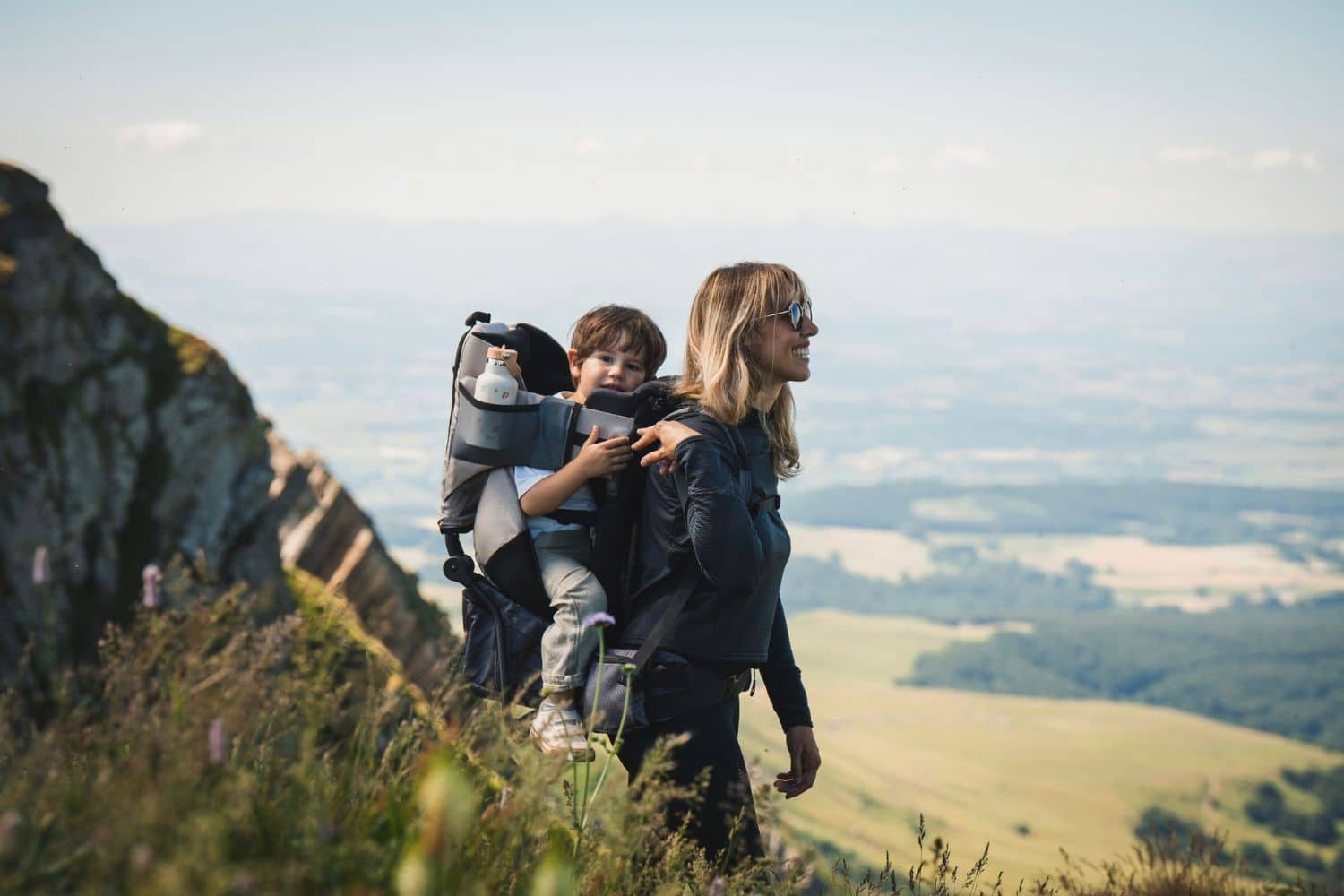 Mère en randonnée portant son enfant en montagne